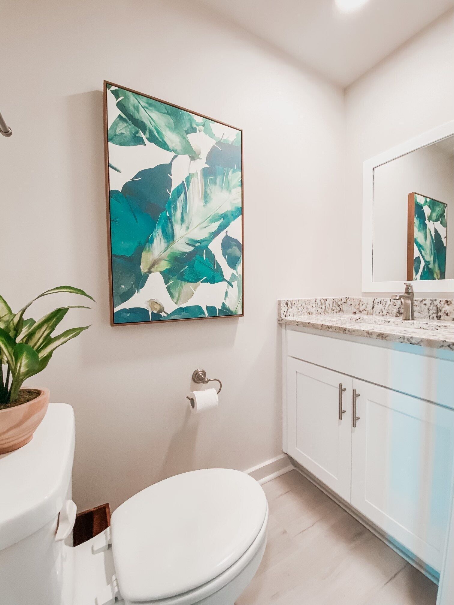 Une salle de bain avec des toilettes, un lavabo et un grand tableau abstrait accroché au mur.