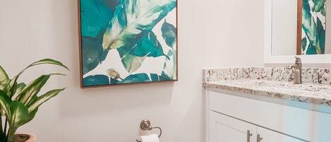 Une salle de bain avec des toilettes, un lavabo et un grand tableau abstrait accroché au mur.