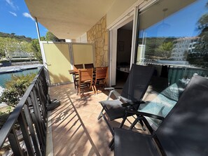 Enjoy the serene view of the water from this balcony with a table, chairs, and sofa.