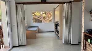 Une pièce spacieuse dotée d’une porte coulissante donnant sur un balcon, d’un banc intégré et offrant une vue sur les arbres.