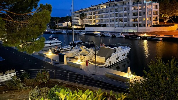 Un port de plaisance avec des bateaux amarrés, un immeuble doté de balcons et un ciel dégagé.