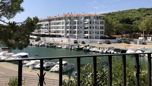 Un immeuble à plusieurs étages doté de balcons, une marina avec des bateaux et un ciel dégagé.