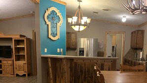 A rustic kitchen with a wooden island, a blue accent wall, and a chandelier. - Entire House - Relax and Ride at Grace Ranch (Victoria)
