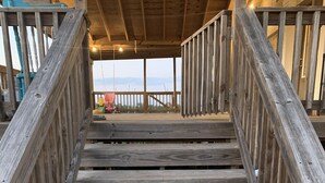 A wooden staircase leading to a covered area with a view of the sea. - Entire House - Relax and Ride at Grace Ranch (Victoria)