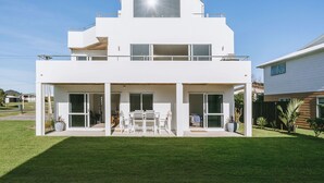 Ein modernes, zweistöckiges Haus mit flachem Dach, großen Fenstern und einer überdachten Terrasse.