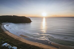 A coastal landscape with a beach, ocean, and a forested hill. - BEACH HOUSE_Whangamatā  (APARTMENT) - 100m from Harbour (Whangamata)
