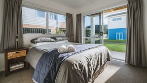 Ein Schlafzimmer mit einem großen Bett, einem Nachttisch, einem Korbwägelchen und Blick ins Freie.