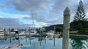 Ein Yachthafen mit vertäuten Booten, ruhigem Wasser und einem Holzpfahl im Vordergrund.