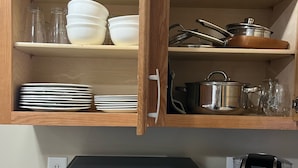 Eine Küche mit Mikrowelle, Kaffeemaschine und Holzschränken, in denen Geschirr und Kochutensilien aufbewahrt werden.