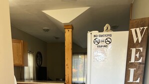 Eine Küche mit Holzschränken, einem weißen Kühlschrank und einem 'WELCOME'-Schild.