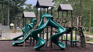 Ein Spielplatz mit grünen Rutschen und Klettergerüsten.
