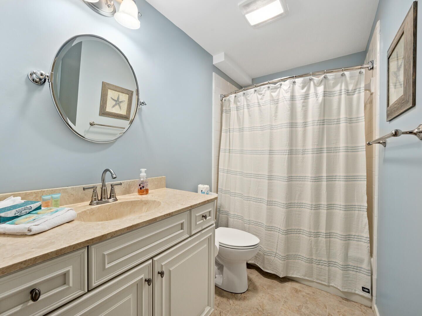 A bathroom with a sink, mirror, toilet, and a shower curtain.