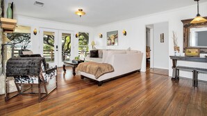 Una habitación amplia con una cama grande, piso de madera, un comedor y vistas al exterior.