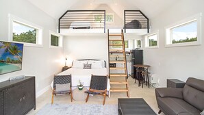 Un espace de vie compact et moderne comprenant une chambre en mezzanine, un coin repas et une kitchenette.