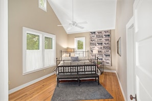 A bedroom with a bed, a ceiling fan, and a wall with a cow print wallpaper.