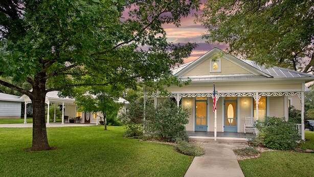 A single-story house with a porch, a front yard, and a driveway. - Oma Lange's Guesthouse | In Town | Hot Tub |  Full Kitchen | WiFi (Fredericksburg)