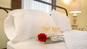 A bed with white linens, two glasses of white wine, and a red rose on a tray. - Oma Lange's Guesthouse | In Town | Hot Tub |  Full Kitchen | WiFi (Fredericksburg)