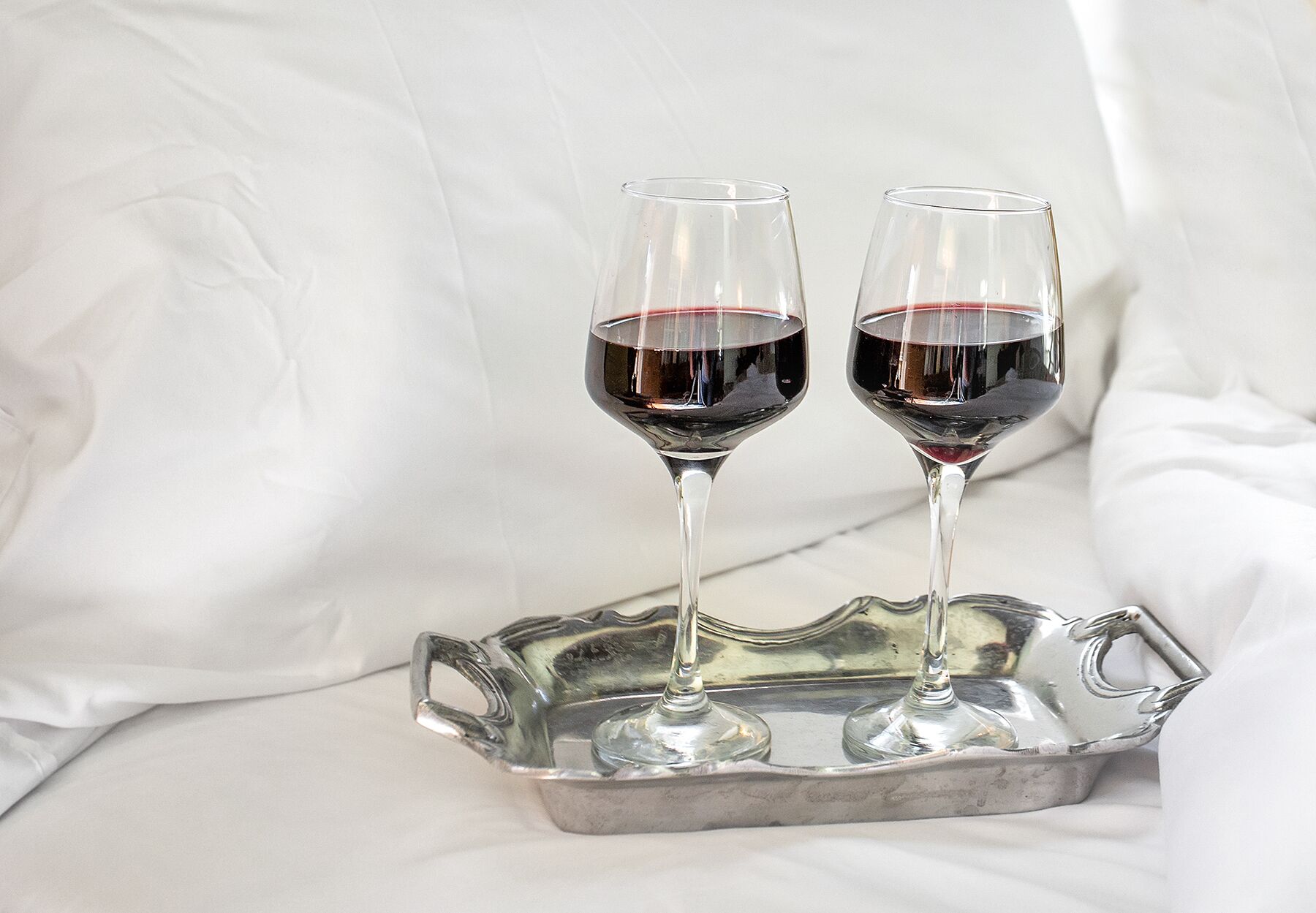 Two wine glasses on a metallic tray.