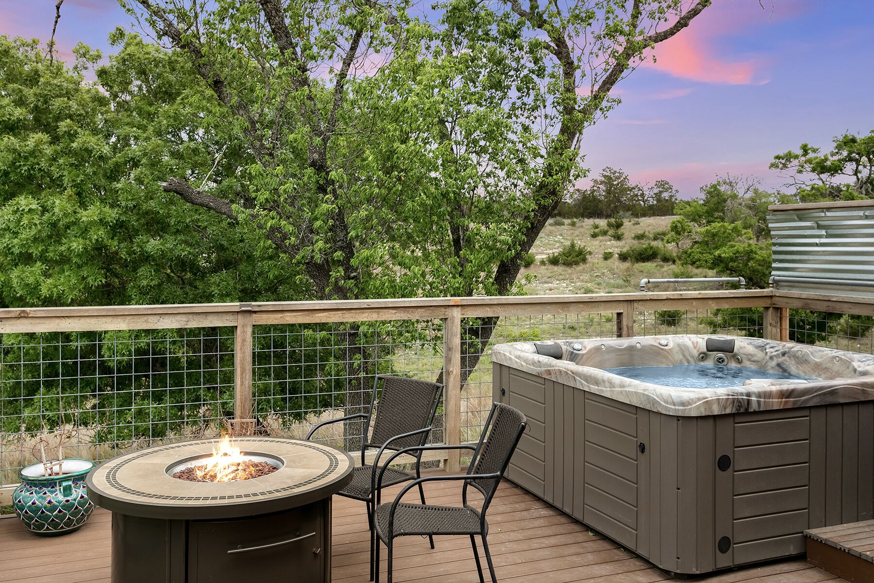 A deck with a hot tub, outdoor seating, and a fire pit.
