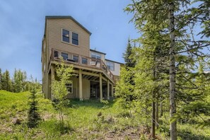 A two-story house with a balcony, surrounded by trees and greenery. - 4BR Townhome w/ Private Hot Tub, Garage, and Deck (Silverthorne)