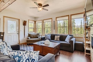 A spacious living room with a large sofa, a coffee table, and a ceiling fan.