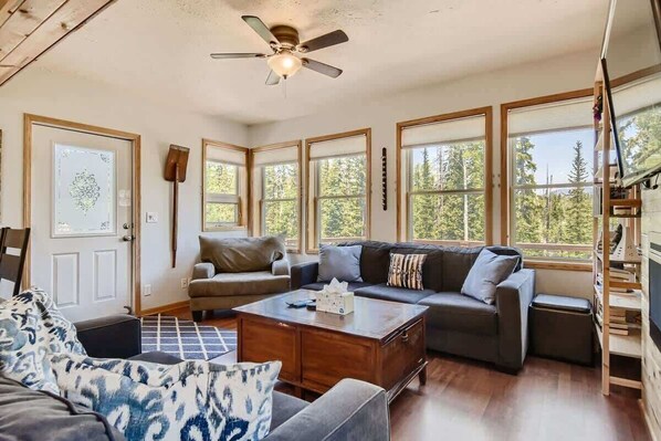 A spacious living room with a large sofa, a coffee table, and a ceiling fan.