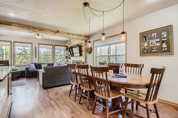 A spacious living area with a wooden dining table, several chairs, a sofa, and a television. - 4BR Townhome w/ Private Hot Tub, Garage, and Deck (Silverthorne)