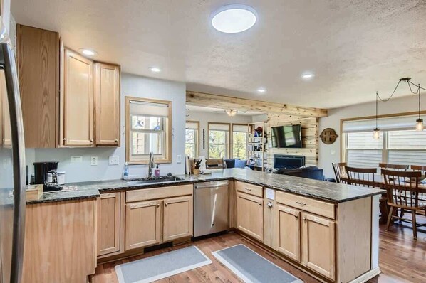 A modern kitchen with wooden cabinets, a large island, and built-in appliances. - 4BR Townhome w/ Private Hot Tub, Garage, and Deck (Silverthorne)