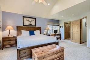 A bedroom with a large bed, wooden headboard, bedside lamps, a wooden chest, and a ceiling fan. - 4BR Townhome w/ Private Hot Tub, Garage, and Deck (Silverthorne)