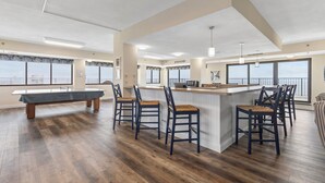 A spacious kitchen with a central island, bar stools, and a pool table.