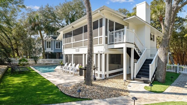 Une maison à deux étages avec un balcon, une piscine et une pelouse bien entretenue.