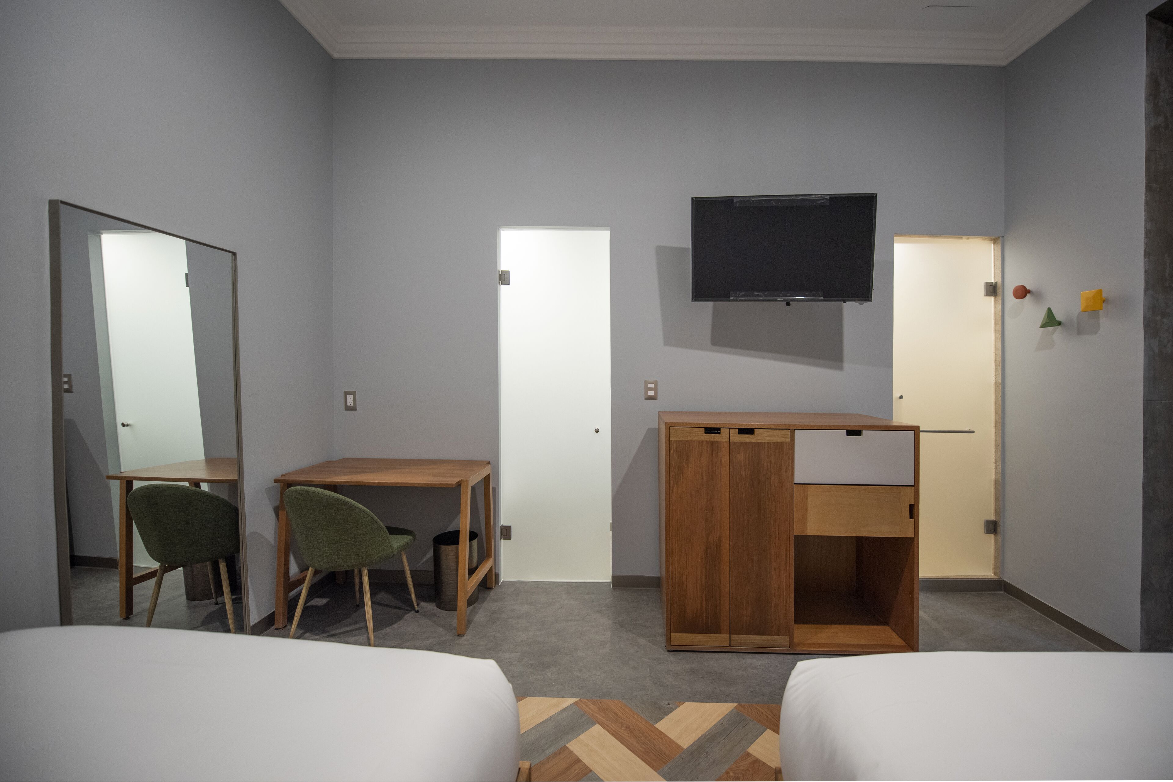 A hotel room with two beds, a desk, a chair, a TV, and a wardrobe.
