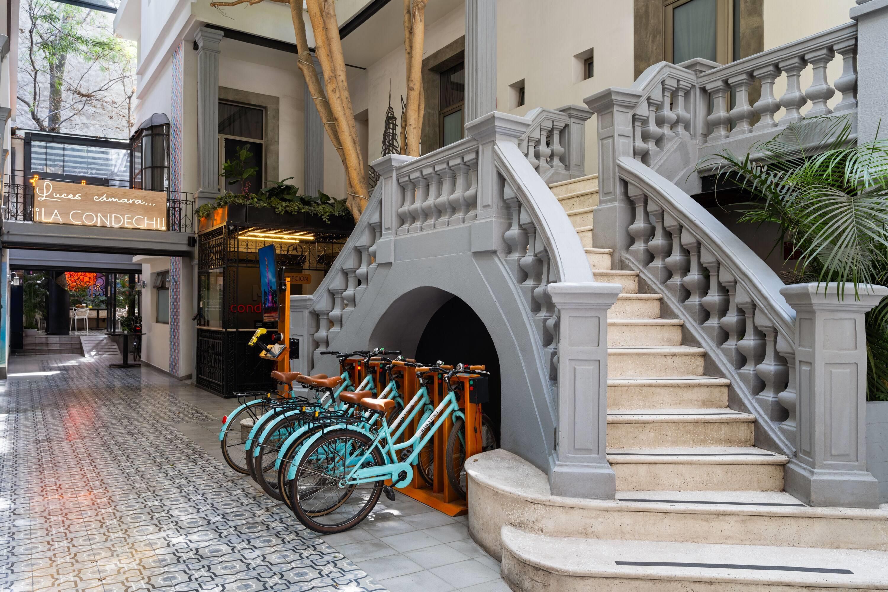 A staircase with a balustrade, a bicycle parking area with turquoise bicycles, and a sign for 'LA CONDECH'.