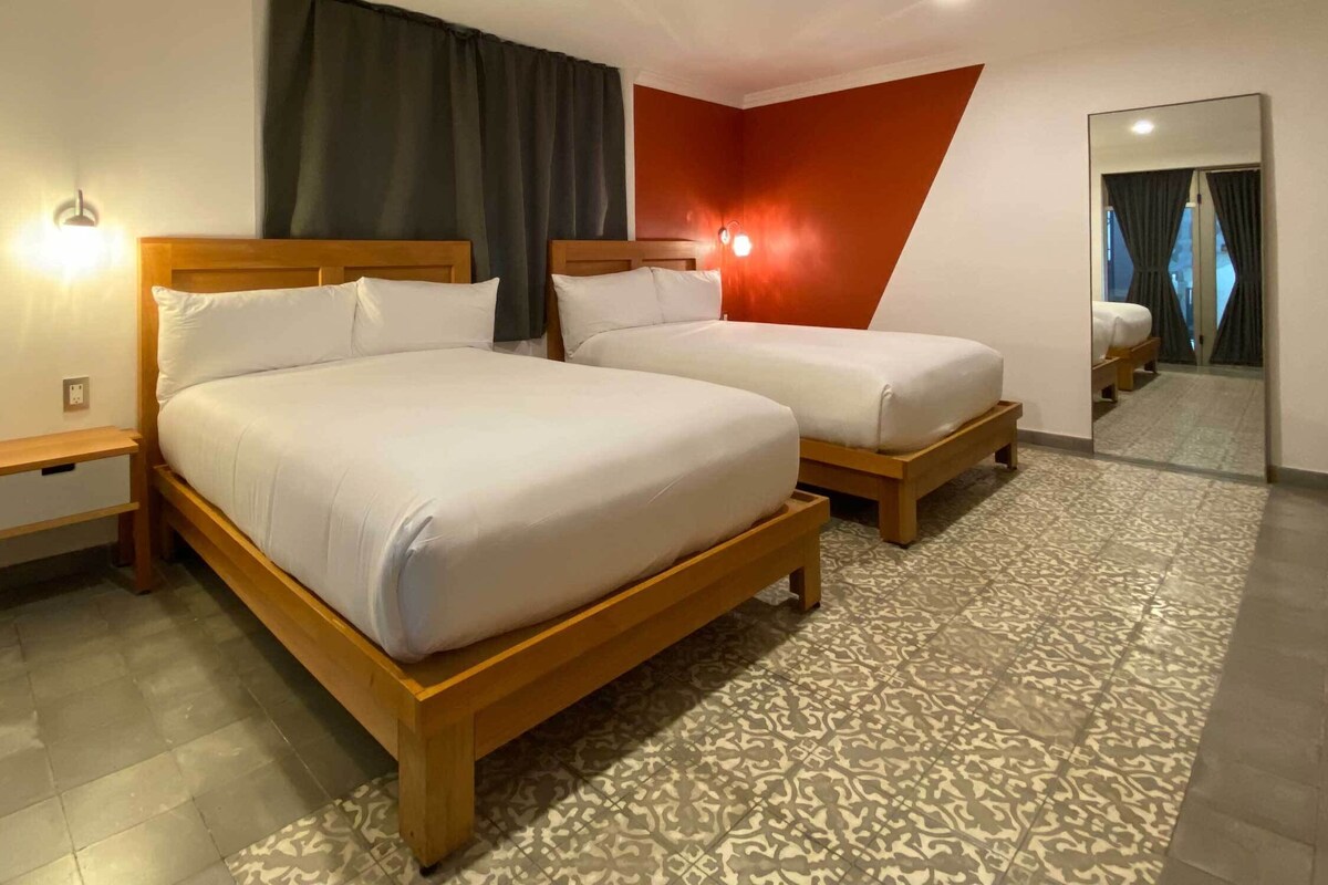 Una habitación de hotel con dos camas de madera, un suelo estampado y un espejo en la pared.