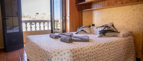 A bedroom with a bed, a balcony, and wooden shelves.