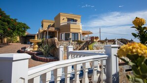 Une maison à deux étages avec un balcon, une fontaine et un mur en pierre.
