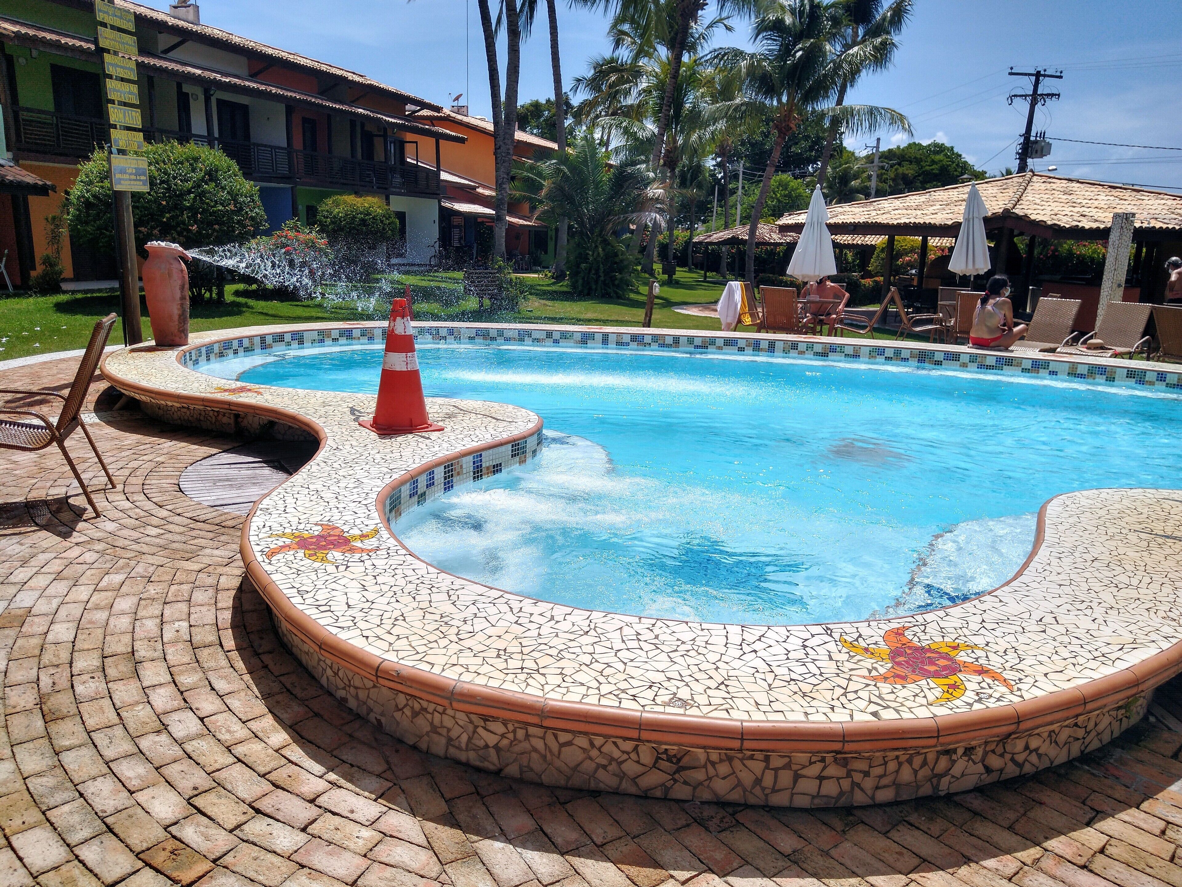 Piscina com borda azulejada, rodeada por um pátio de tijolos.