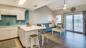 Una cocina moderna con una isla central, armarios blancos y un salpicadero verde azulado.