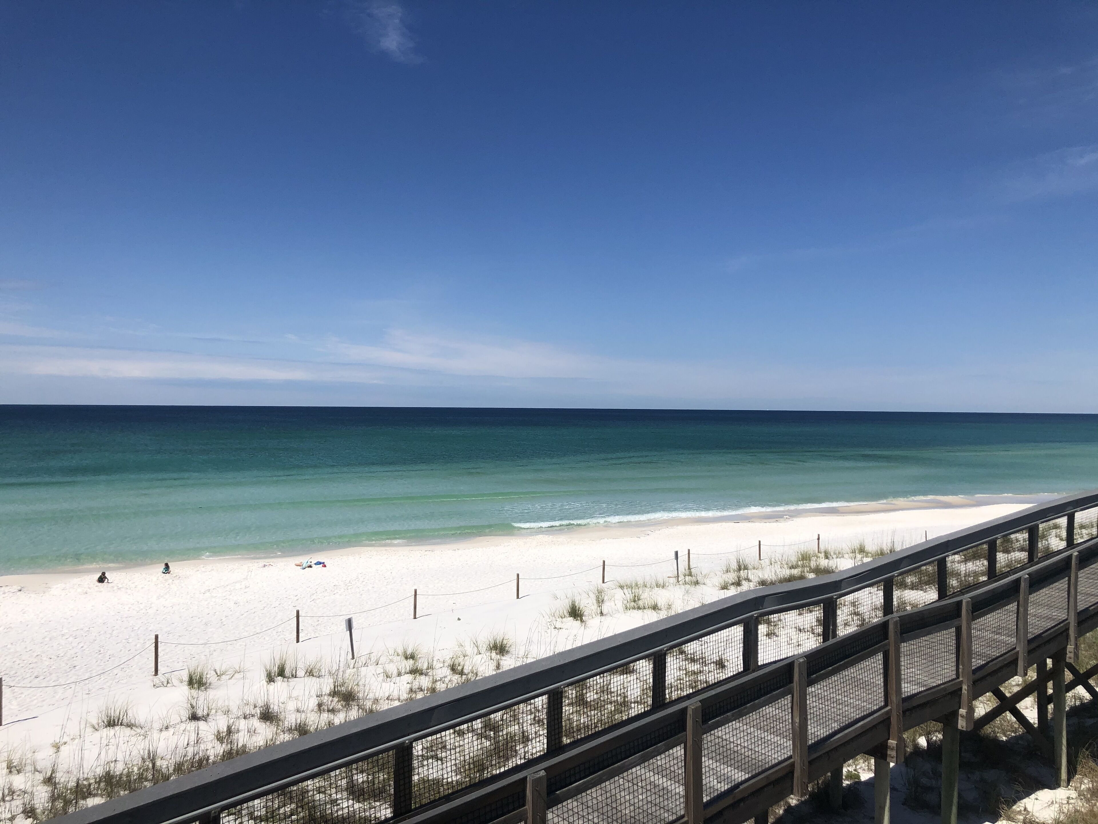 A beach with a wooden boardwalk leading to the shore.
