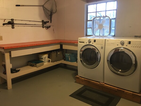 A laundry room with two washing machines, a window, and a shelf with storage bins.