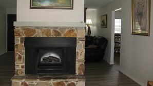 Una sala de estar con chimenea de piedra, un cuadro en la parte superior y un sofá al fondo.