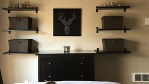 Une chambre à coucher comprenant un lit, une commode et deux étagères murales avec des boîtes de rangement.