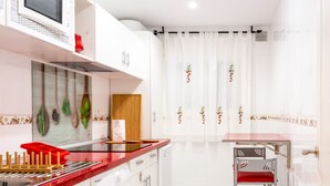 A compact kitchen with a washing machine, a microwave, and a dining area with a chair. - El Rincón de Maria y Pedro (Torremolinos)
