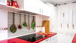 A modern kitchen with white cabinets, a red countertop, and wooden utensils hanging on the wall. - El Rincón de Maria y Pedro (Torremolinos)