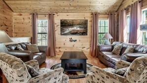 A log cabin interior with leather sofas, patterned chairs, a central table, and a painting of a forest stream. - 10 Mins to Downtown Gatlinburg~HotTub~Rockytop (Gatlinburg)
