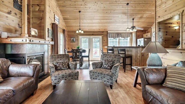 A cozy cabin interior with a fireplace, leather sofas, patterned armchairs, a dining area, and a kitchen. - 10 Mins to Downtown Gatlinburg~HotTub~Rockytop (Gatlinburg)