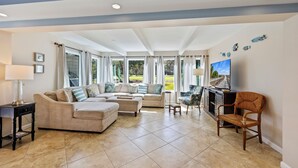 A spacious living room with a beige sectional sofa, a wooden chair, and a TV on a stand. - SeaPines, Remodeled, Lovely Golf View, Pet Friendly (Hilton Head Island)