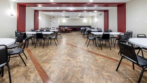 A conference room with multiple tables and chairs, a tiled floor, and a red accent wall. - HomeTowne Studios by Red Roof Bordentown - McGuire AFB (Bordentown)