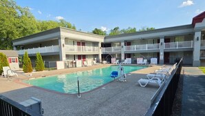 A motel with a swimming pool, multiple balconies, and a fenced deck area. - HomeTowne Studios by Red Roof Bordentown - McGuire AFB (Bordentown)