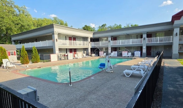 A motel with a swimming pool, multiple balconies, and a fenced deck area. - HomeTowne Studios by Red Roof Bordentown - McGuire AFB (Bordentown)